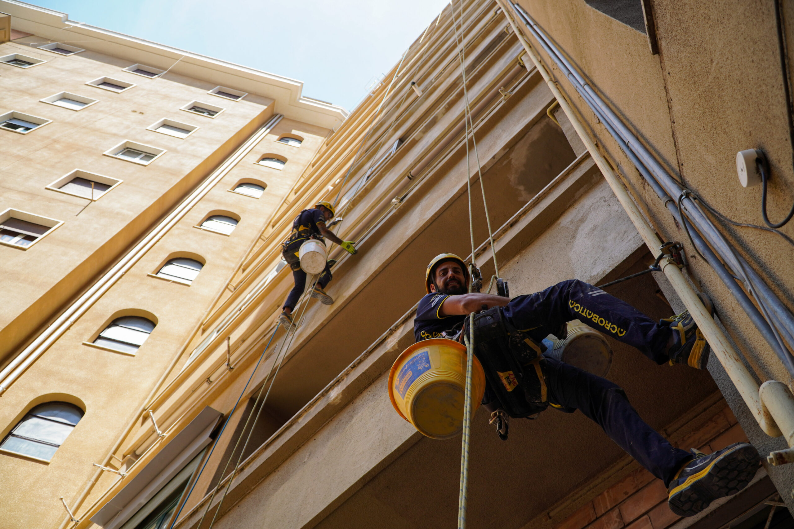 tecnici di acrobatica su fune davanti alla facciata di un condominio