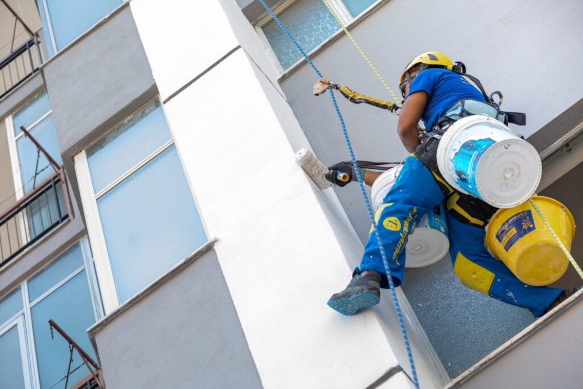 Condominio in fase di ristrutturazione con operaio che ridipinge facciata.