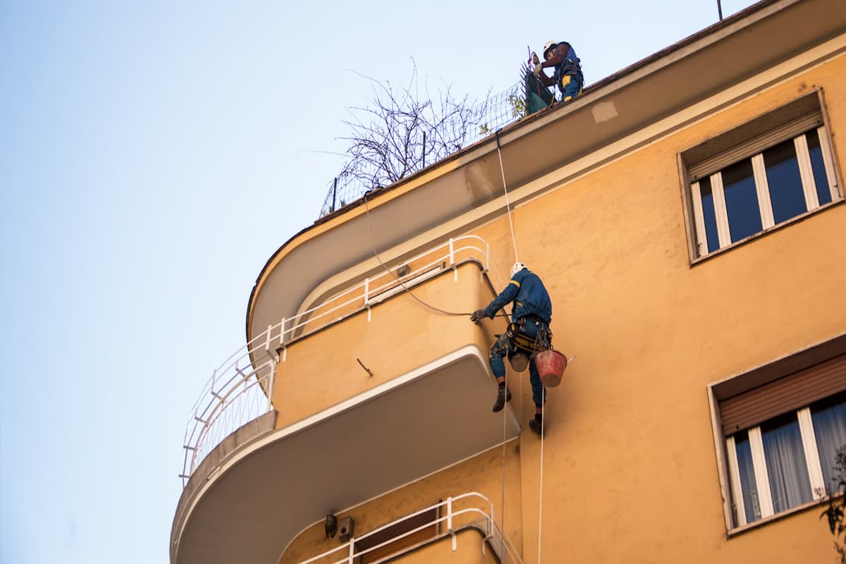 operaio acrobatica su fune mentre sale su balcone condominiale