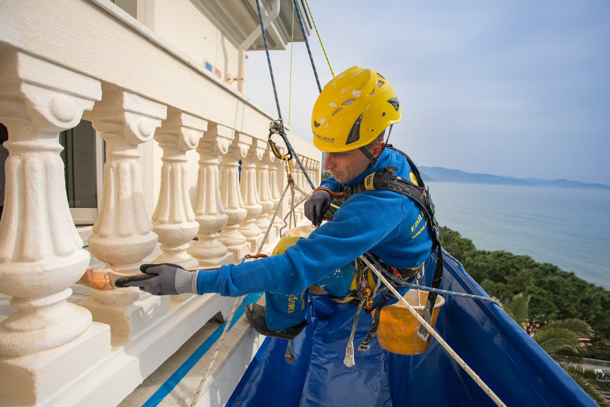 uno degli step di procedura per impeabilizzare il balcone (applicazione primer) con operaio di Acrobatica in primo piano