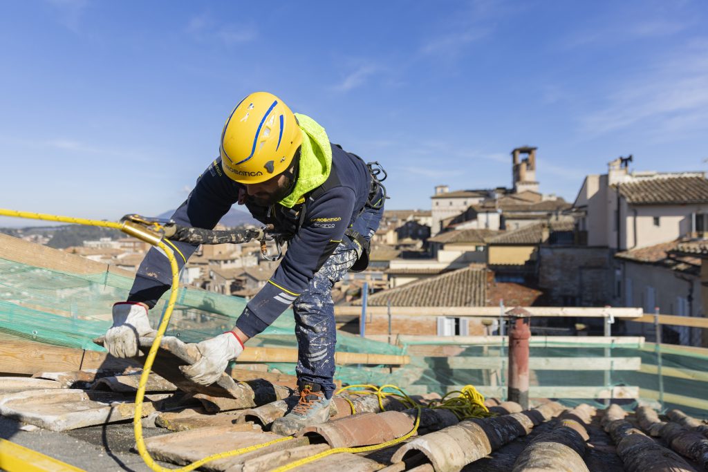 Operaio di Acrobatica intento a risolvere un problema di infiltrazione d'acqua piovana su un tetto